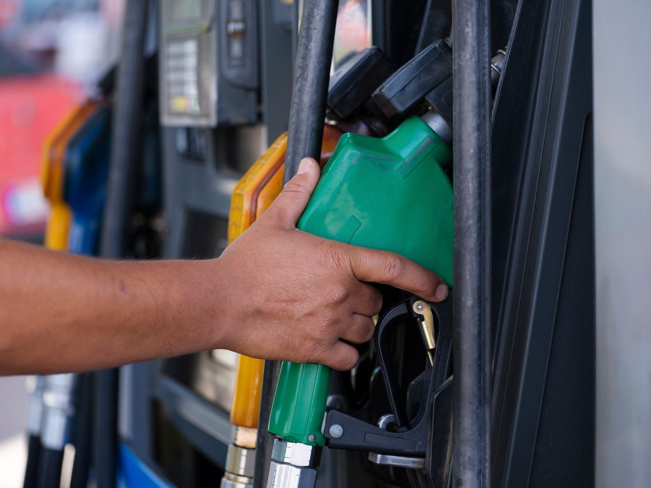 Hand holding a fuel nozzle at the pump