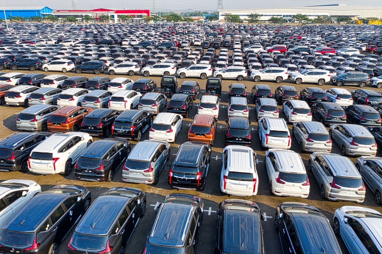 Aerial view of a vehicle distribution yard beside a factory